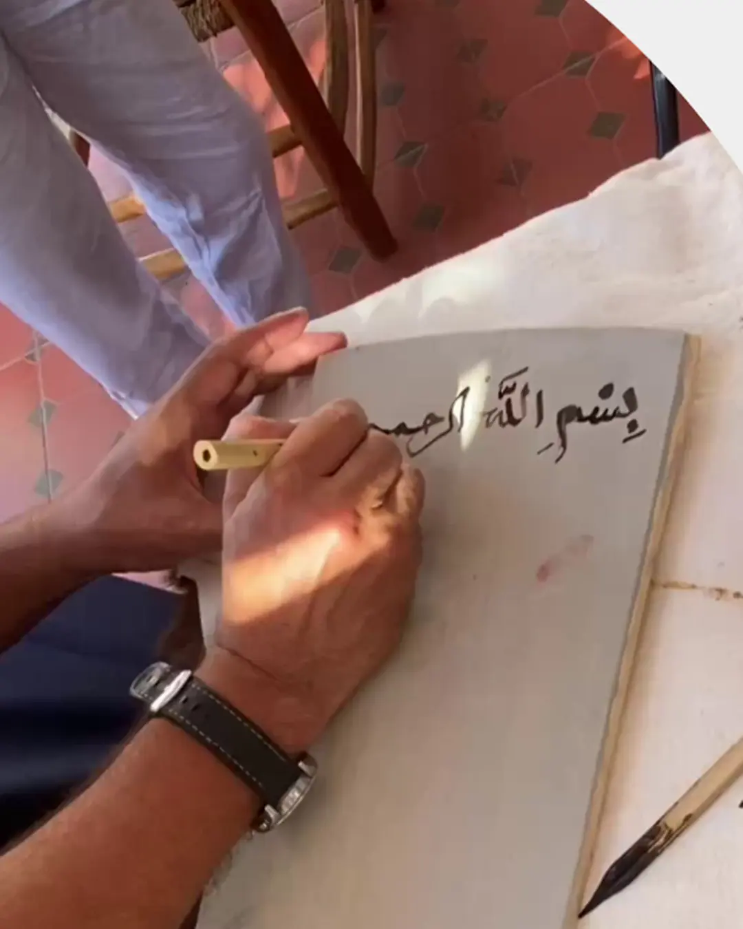 يد تكتب الخط العربي بقلم القصب على الورق