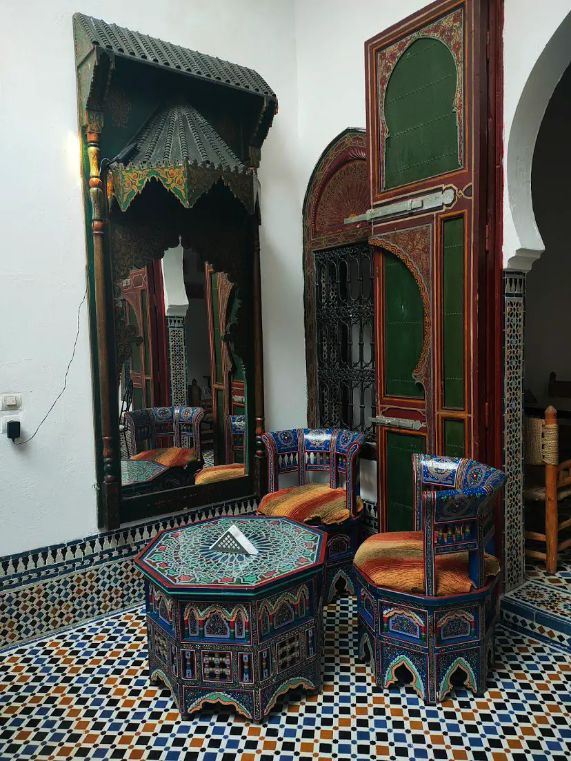 Painted Moroccan chairs, carved mirror and zellige floor inside Dar La Medina Tetawen