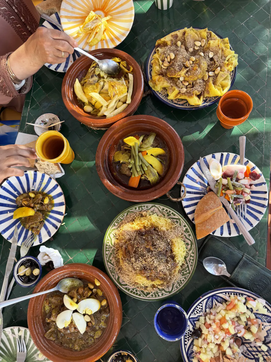 Moroccan tagines, couscous and tea shared on a green tiled table