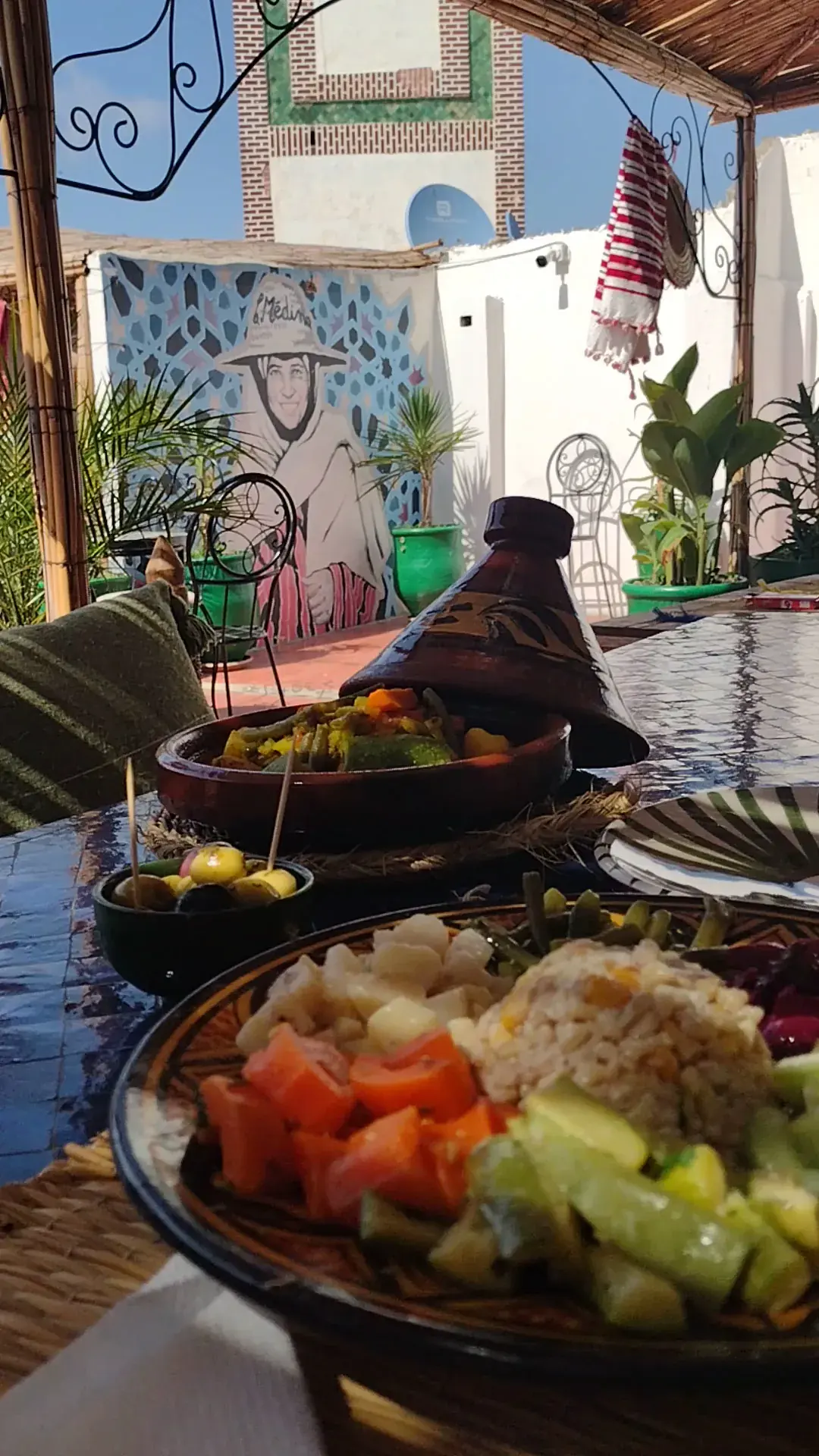 Rooftop table with Moroccan tagine, salad and a Tetouan mural