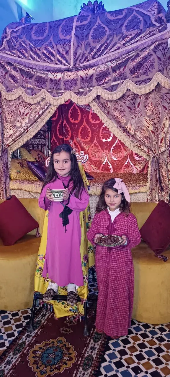Two girls sharing tea and dates during a school visit at Dar La Medina Tetawen